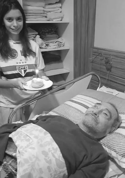 Caroline leva uma vela e um pequeno doce ao avô Ryoki Inoue em seu aniversário de 80 anos
